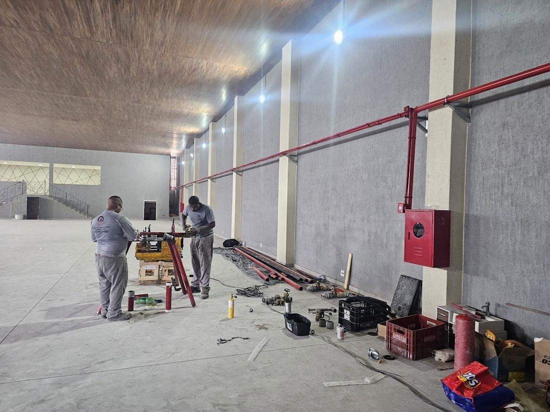 Equipe instalando rede de hidrantes em galpão