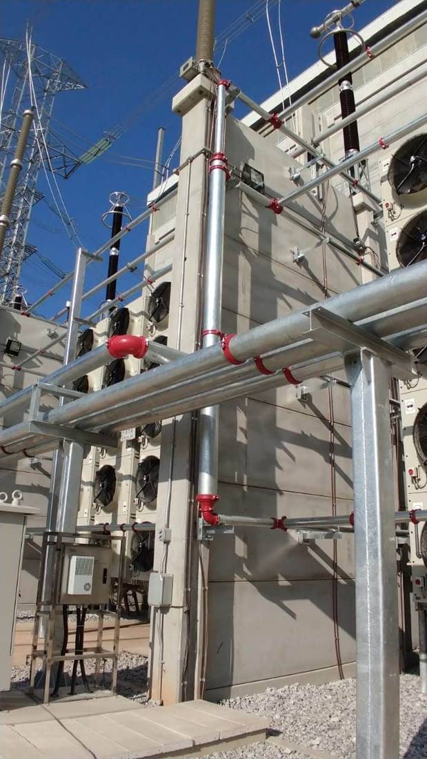 Tubulação galvanizada fixada em estrutura metálica ao lado de equipamentos elétricos
